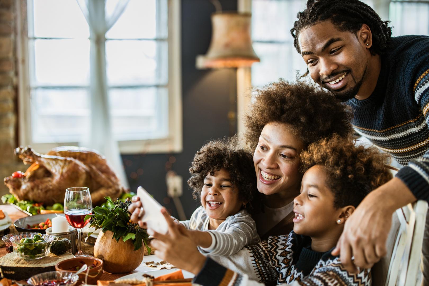 Family at holiday dinner calling someone on their smartphone