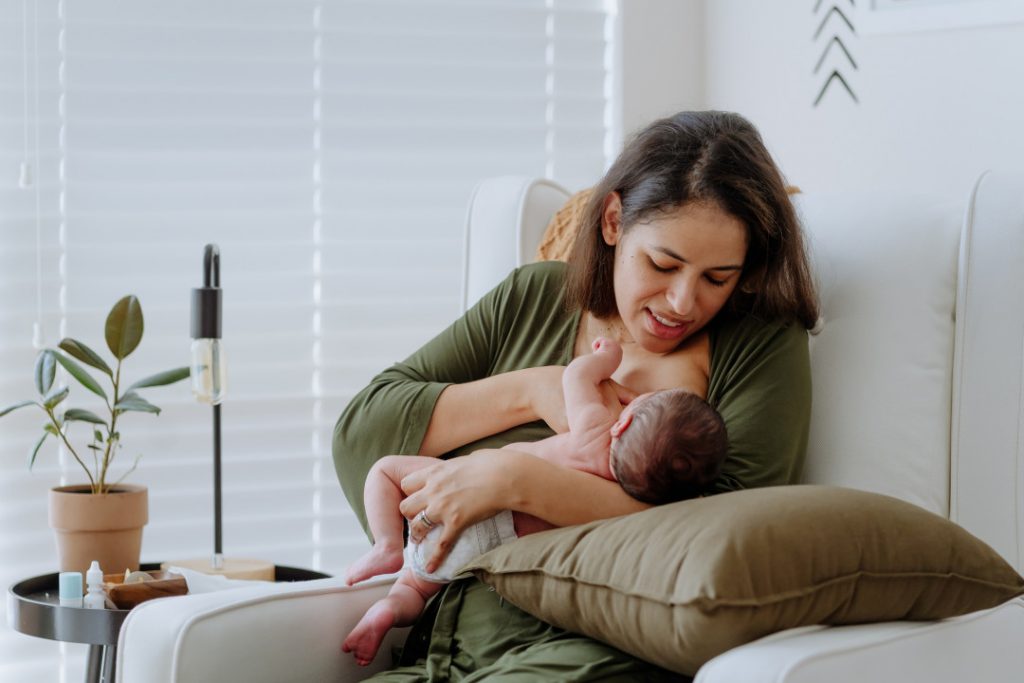 Mother breastfeeding her baby boy in the nursery room