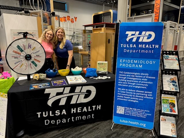 THD's epidemiology team at the Discovery Lab in Tulsa for a back to school night with teachers. Standing in front of table with THD information.